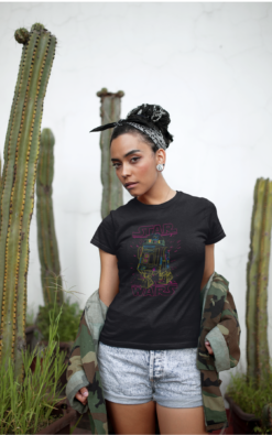 Woman wearing a Star Wars R2-D2 t-shirt, standing confidently in front of tall cacti.