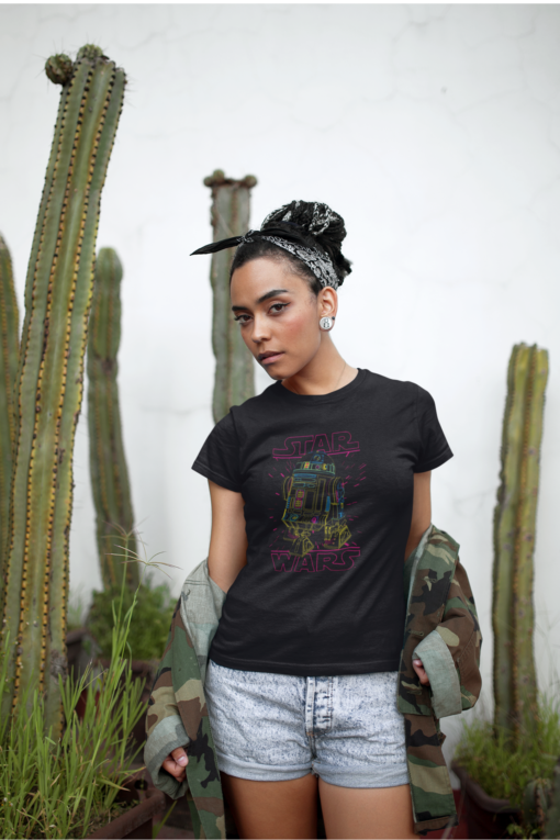 Woman wearing a Star Wars R2-D2 t-shirt, standing confidently in front of tall cacti.