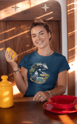 Smiling girl holding a mango and wearing a blue t-shirt featuring a crescent moon design with Studio Ghibli characters.