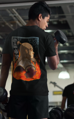 A man lifting weights in a gym while wearing a black Uncle Iroh-themed T-shirt. The design features Uncle Iroh surrounded by flames, a teapot, and elemental symbols from Avatar: The Last Airbender.