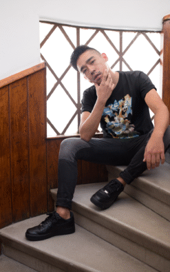 Young Asian man wearing black Pokémon starter trio t-shirt featuring Bulbasaur, Blastoise, and Charizard sitting on stairs