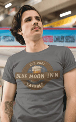 Man wearing Blue Moon Inn Varrock t-shirt casually posed during daytime.
