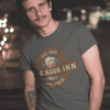 Lifestyle shot of man modeling Blue Moon Inn Varrock unisex t-shirt in casual outdoor setting.