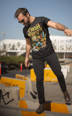 Man wearing Crash Bandicoot casual t-shirt outdoors in an urban setting, balancing on a curb.