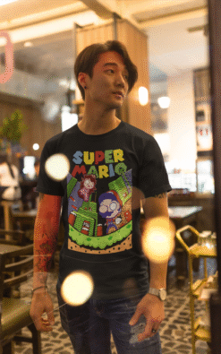 Asian man wearing black Super Mario unisex t-shirt standing in a restaurant with warm lighting