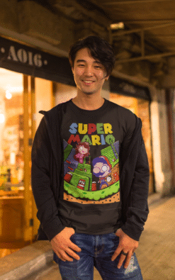 Happy Asian man wearing black Super Mario unisex t-shirt smiling on a city street at night