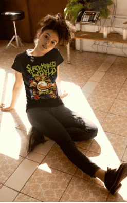 Woman seated on the floor wearing a black Super Mario World heavy metal graphic tee.