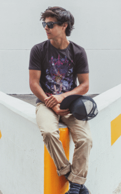 Man sitting on street corner wearing black Yu-Gi-Oh! anime graphic t-shirt